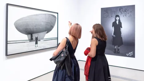 Photo of visitors looking at Shirin Neshat's work.